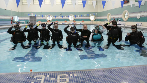 The class, including Peterson and Toft, demonstrate SCUBA hand signals.